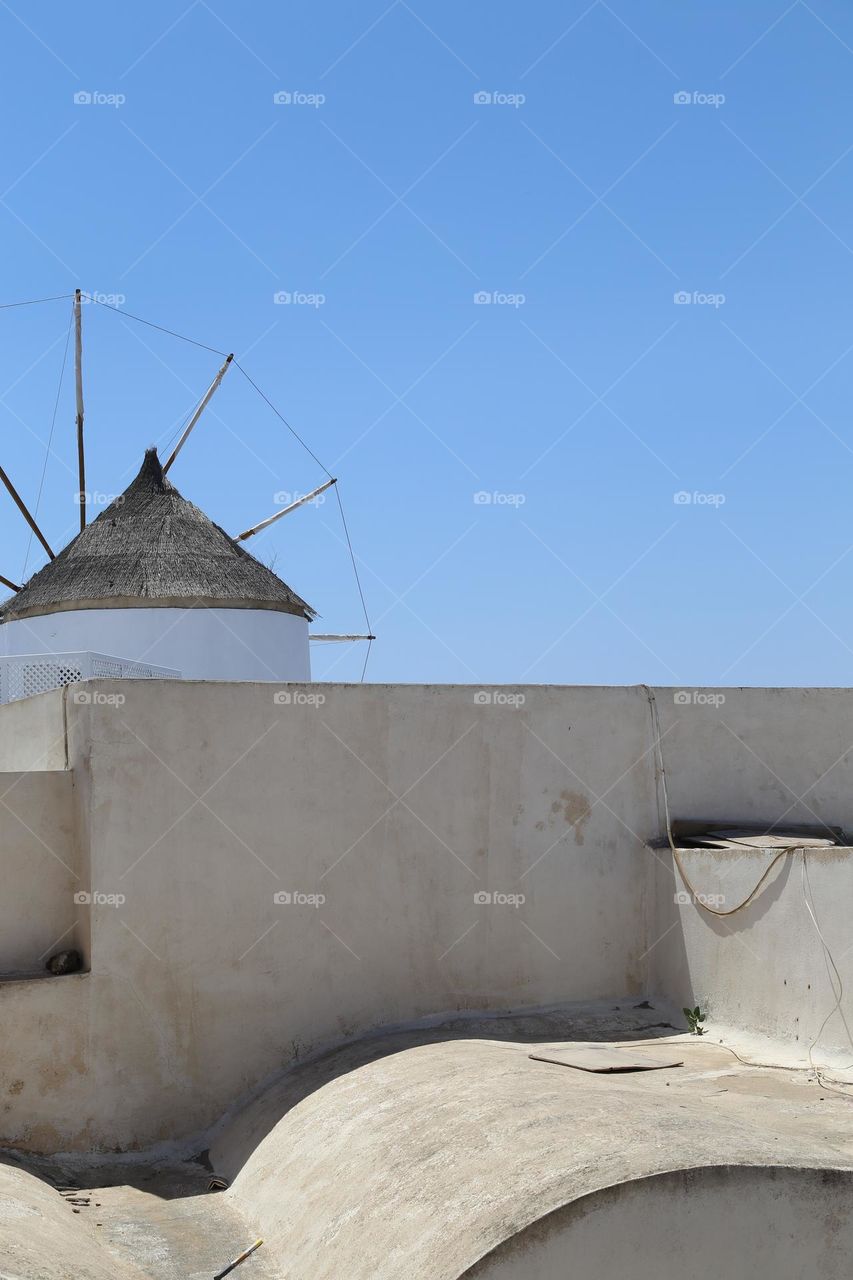 Windmill behind a wall towards the blue sky 