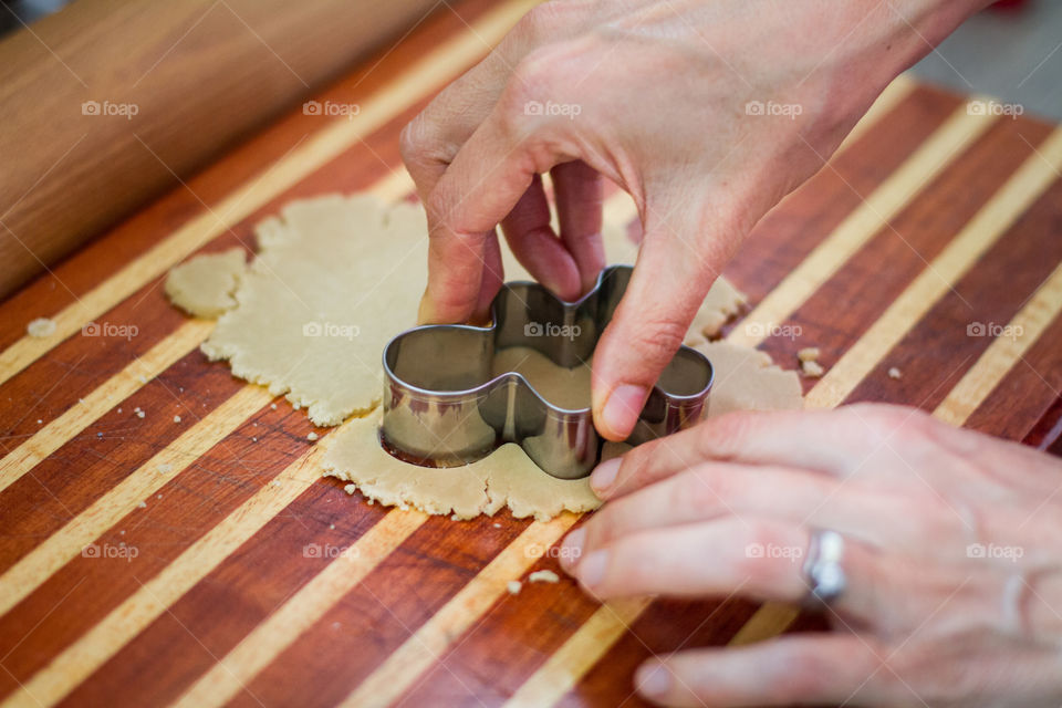 Homemade cookies! Image of woman cutting shapes in cookie dough on a wooden board.