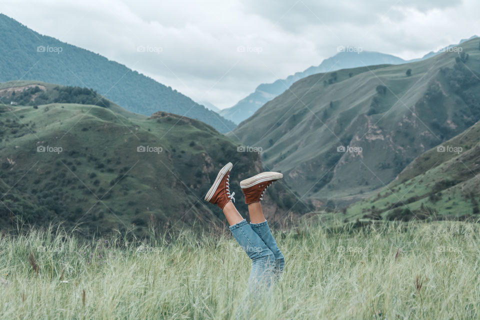 female legs lifted up, meadow in mountains