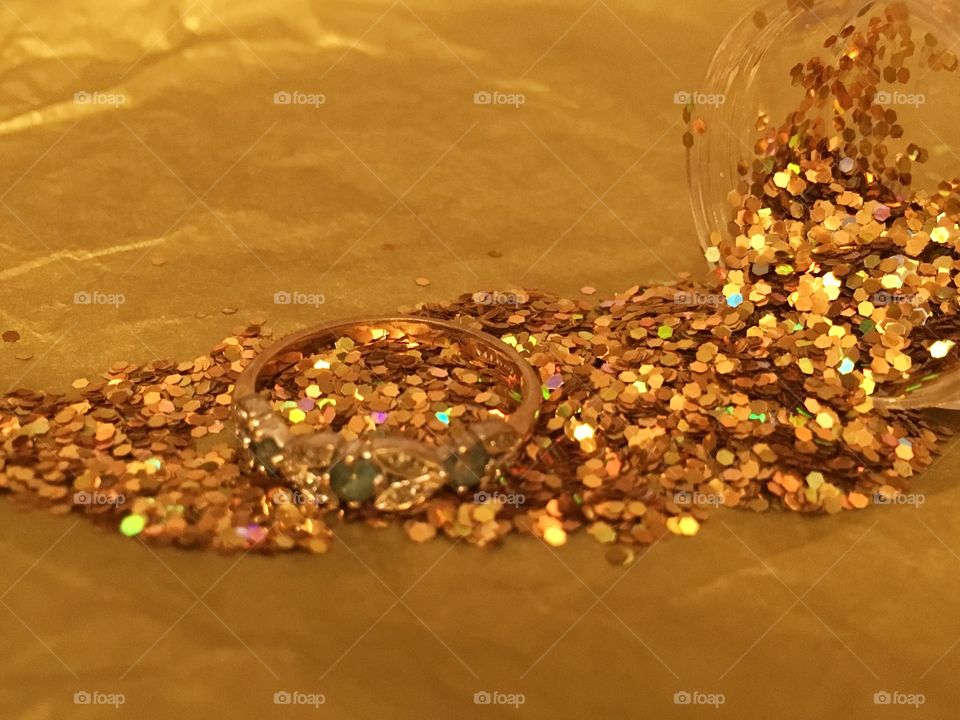 Gemstone gold ring on top of gold glitter spilled onto gold tissue paper 