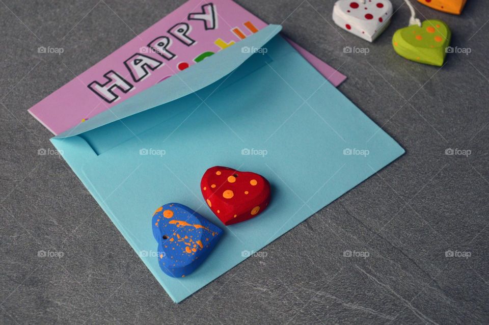 Multicolored wooden hearts near a greeting card