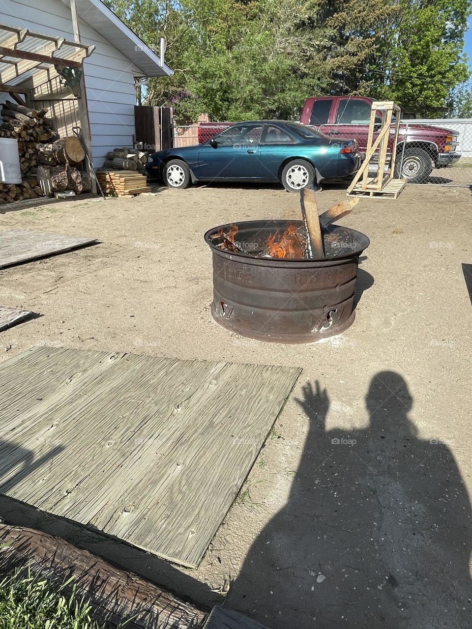 Sitting by the firepit on a sunny day, in summer, waiting for the sun to go down to enjoy the fire, my shadow waving hello, taken on my iPhone 12.