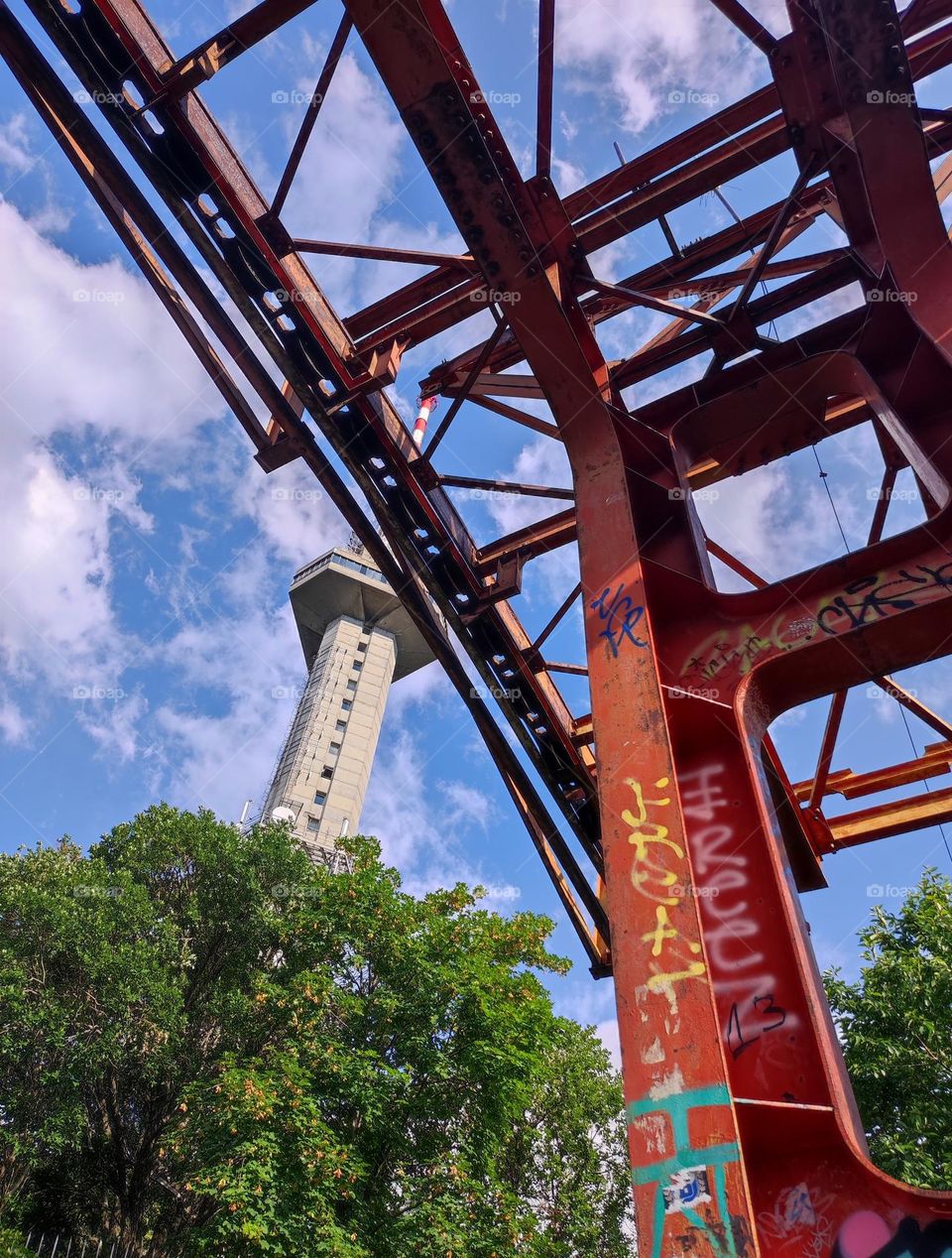 Old metal construction with graffiti, metal colored in red with a cloudy blue sky overhead