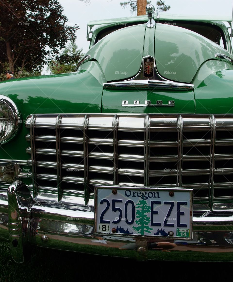 The hood and chrome grill of a classic bright green Dodge pickup at the annual car show in Drake Park in Central Oregon during the summer. 
