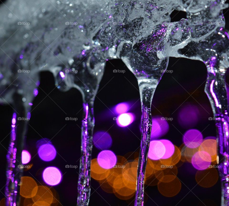 icicles hang from the roof against the backdrop of New Year's lights turned into bokeh