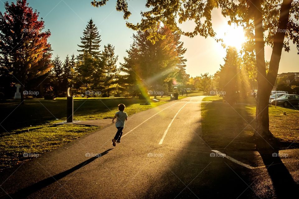 Morning hours sunrise, a small kid running towords sun greenery. 
