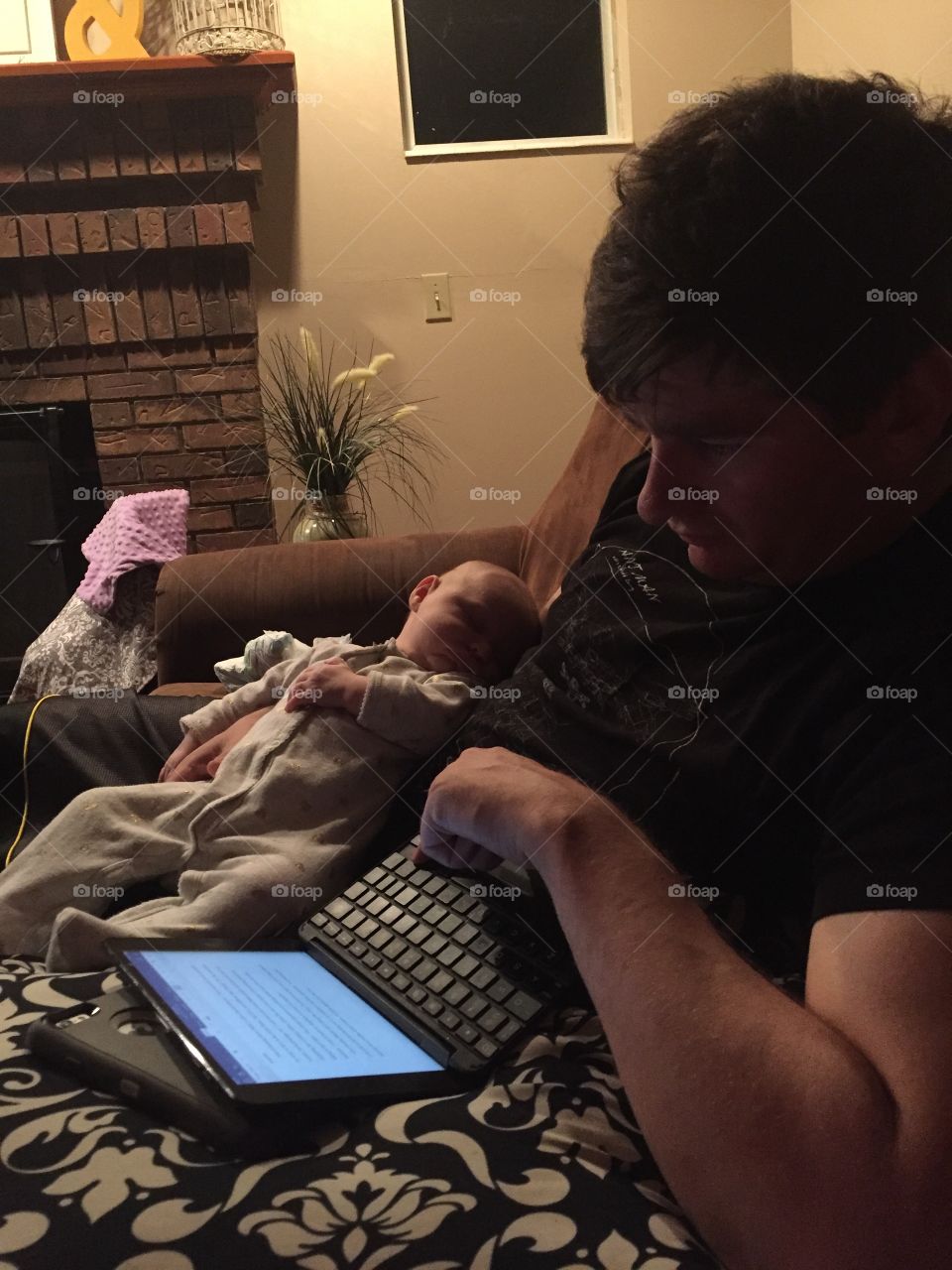 Father holding baby while working