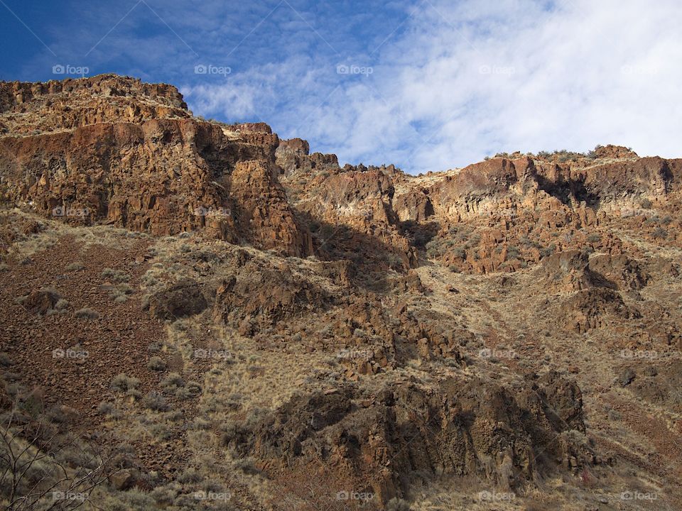 Detailed rock cliffs on a steep hill with nice blue skies in Central Oregon. 