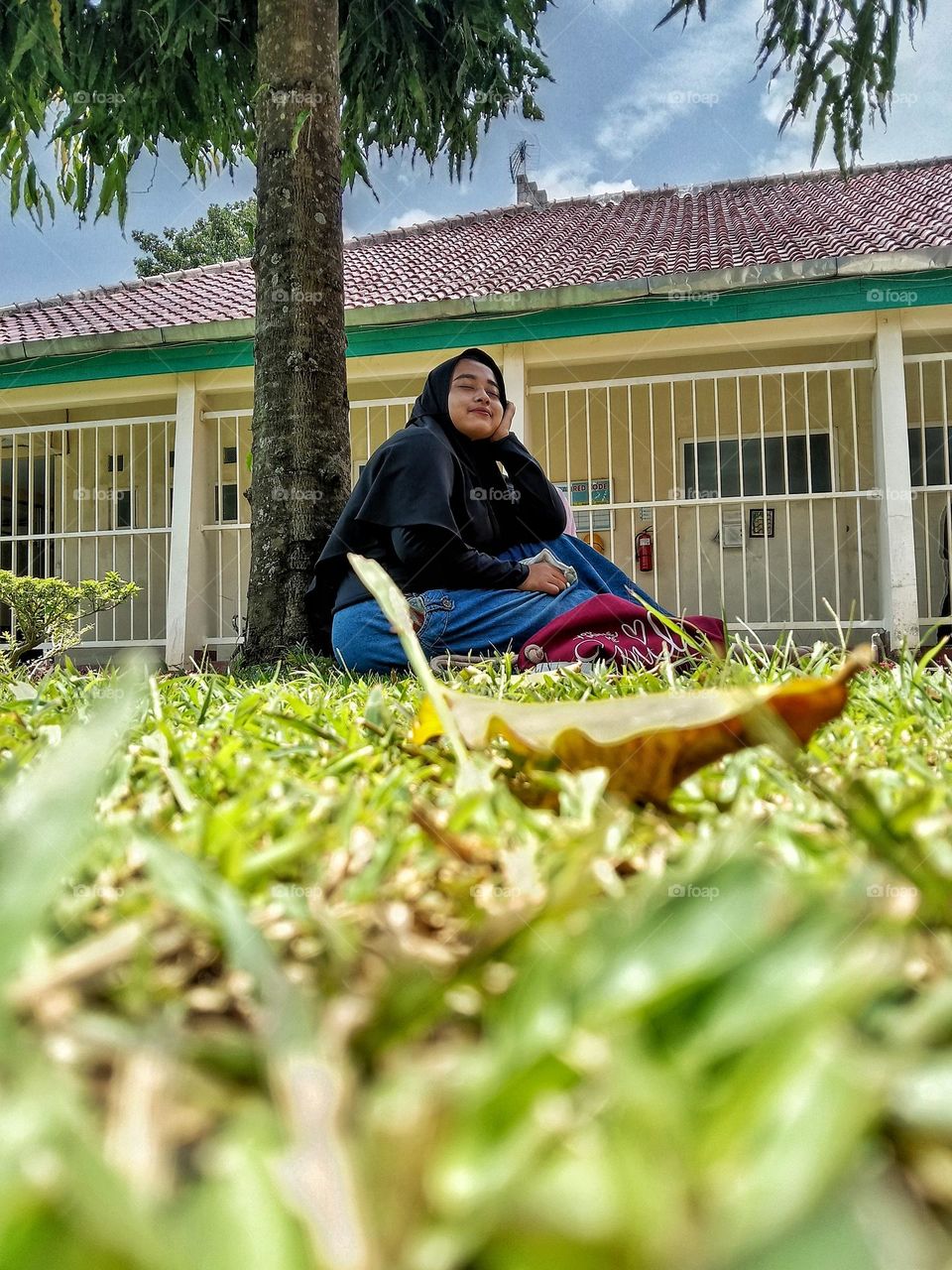 A teenager is relaxing under a tree.