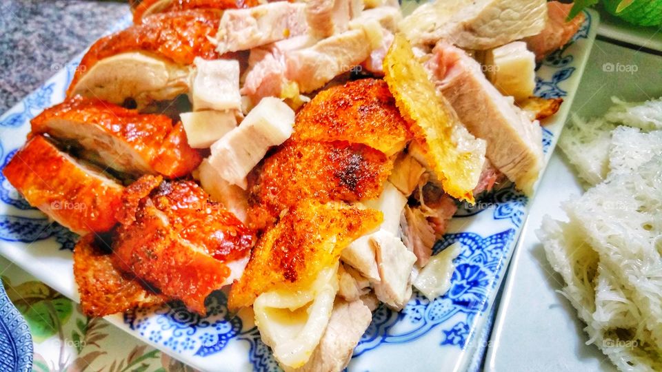 Roast duck and pork pieces on a plate. Some crackling skin portions can be seen on the roast pork. Classic Chinese style cuisine.