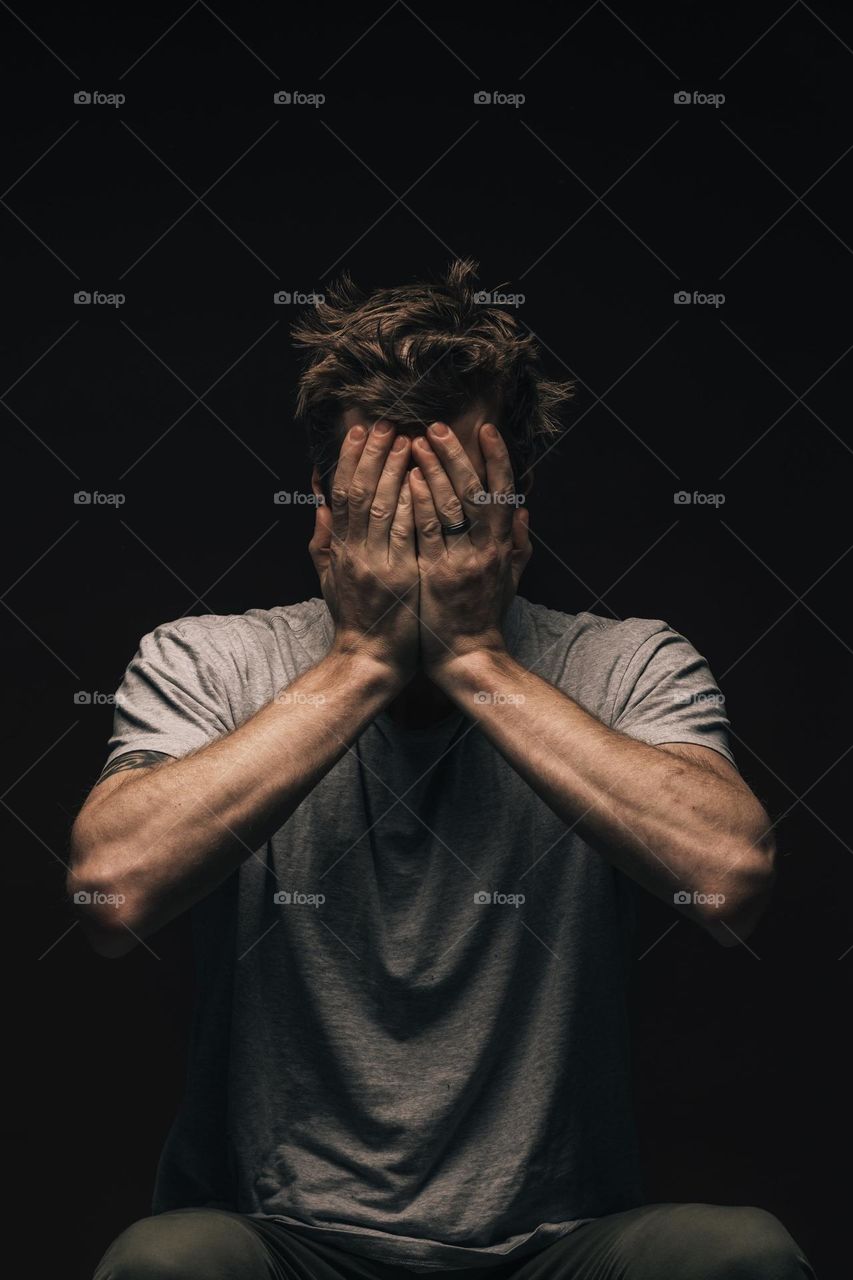 picture of a man covering his face using his two hands