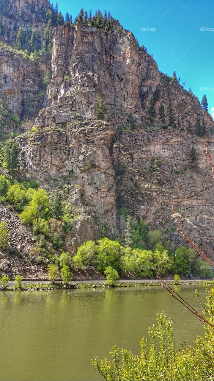 Carved from prehistoric oceans the deep cliffs of Glenwood Canyon stand proud above the tranquil Colorado River.