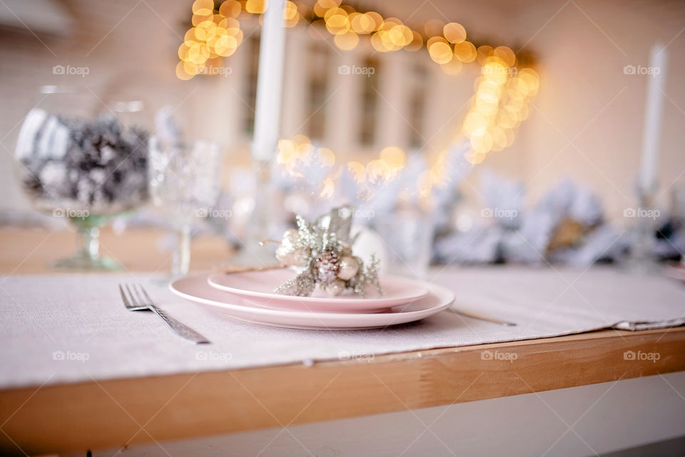 Festive winter cozy kitchen interior with garlands, decorations and gifts.  Christmas dinner at the decorated table.