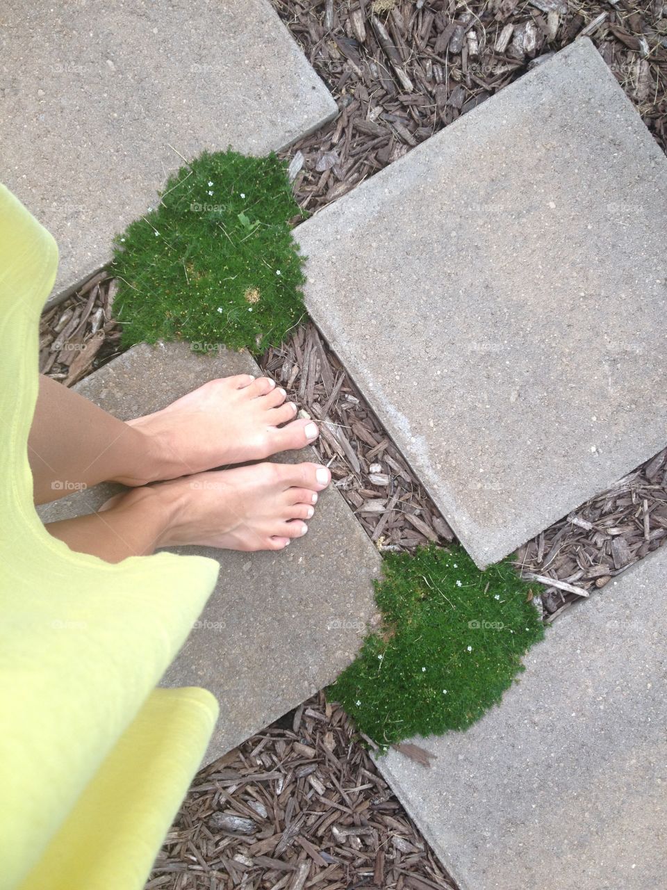 Where I stand: barefoot on pavers,with moss and yellow dress, feet in the garden 