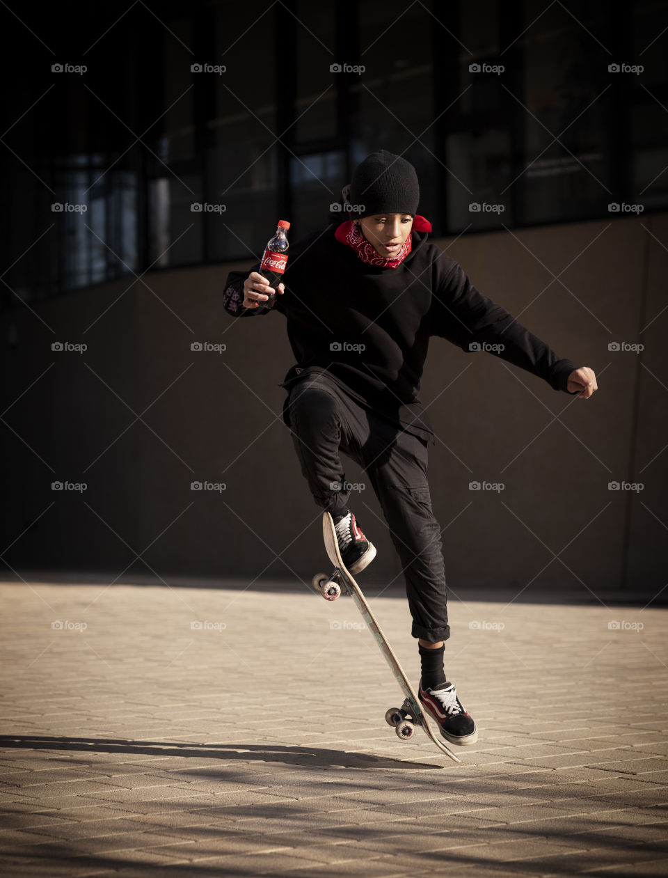 A teenager jumps on a skateboard. With a Coca-Cola in your hand