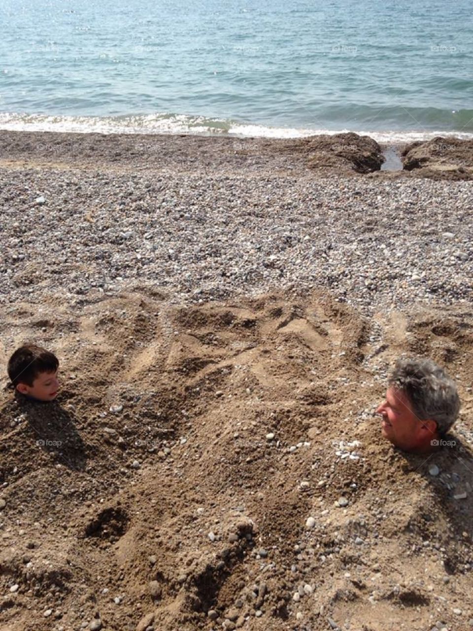 Buried in sand!. My dad and nephew buried in the sand at the beach, laughing. Kodak moment! 