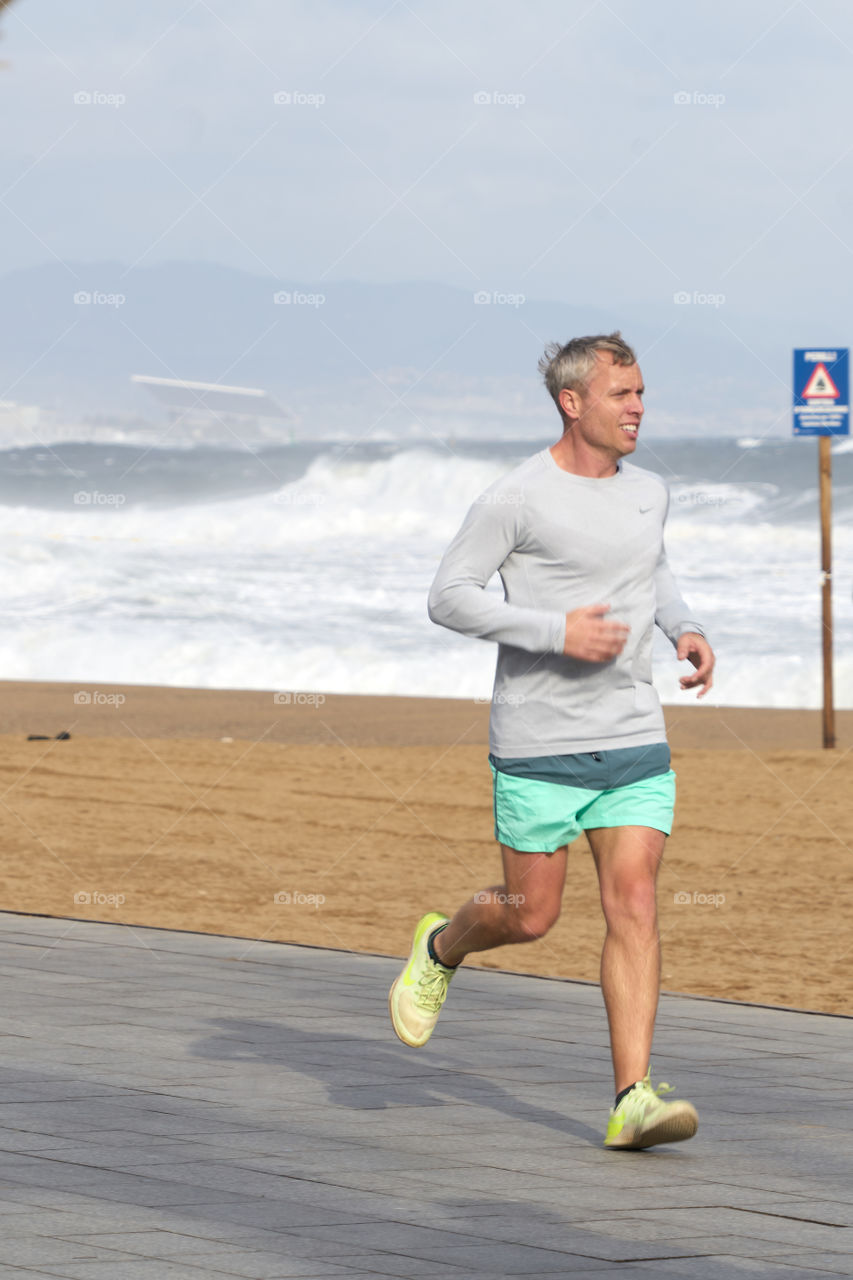 Norwegian man running by the sea in a cold and grey day in Barcelona. It doesn't seems to affect him. 