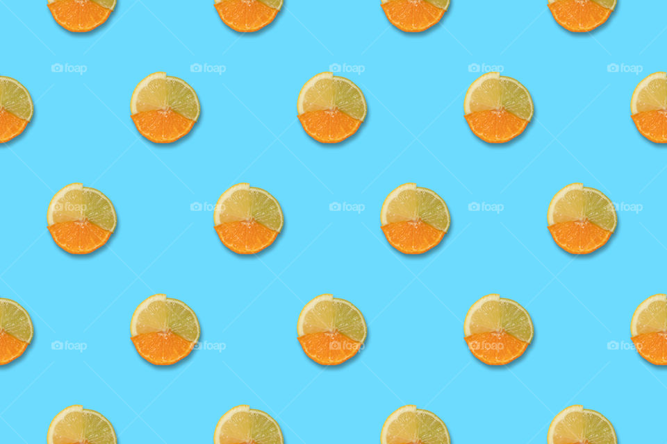 Slices of orange lemon and lime in full fruit arranged in pattern.