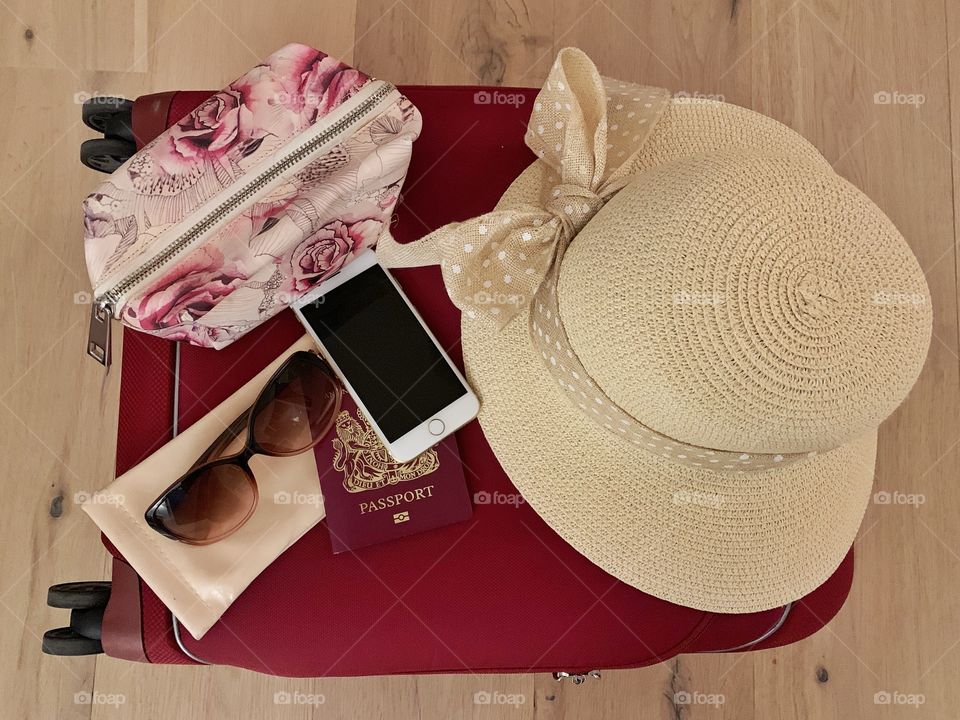 Suitcase with hat, passport, phone, purse and cooling glass 