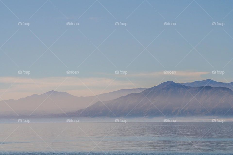 Mountain range seen in the distance across the Salton Sea in Riverside and Imperial counties, with the mist rising off the water giving a watercolor effect