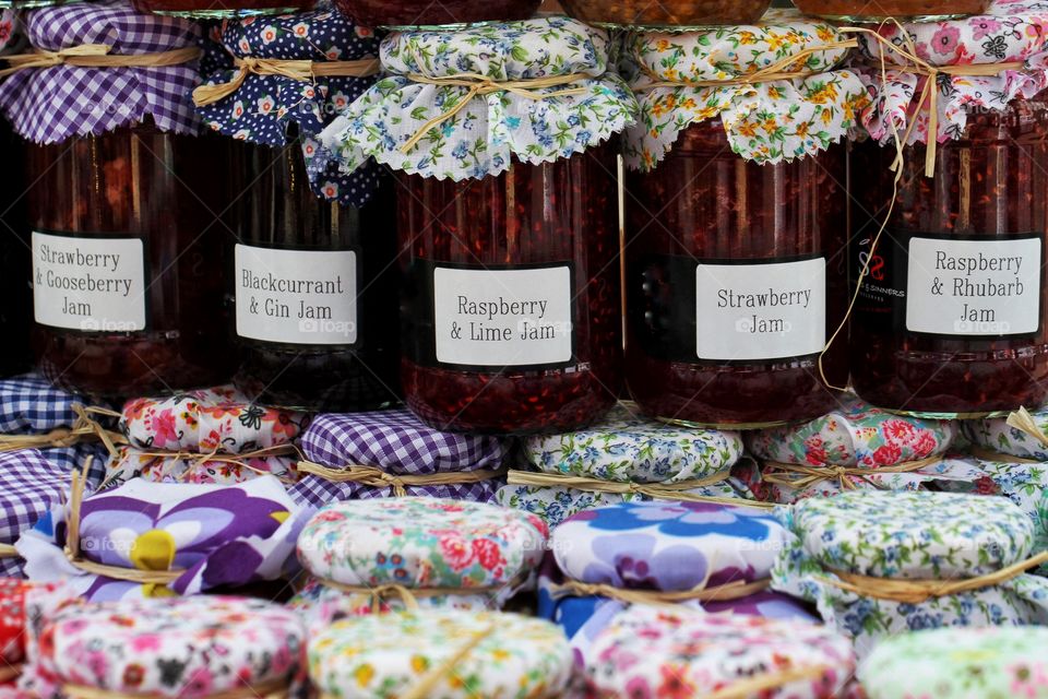 Rows of hand, jellies and preserves with colourful covers on a food market stall.