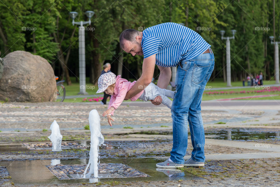 dad and kid are playing with fountain