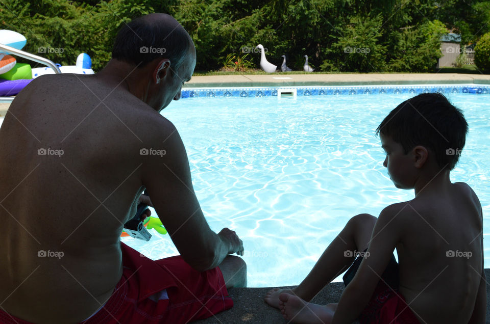 Boy and grandfather sitting poolside together