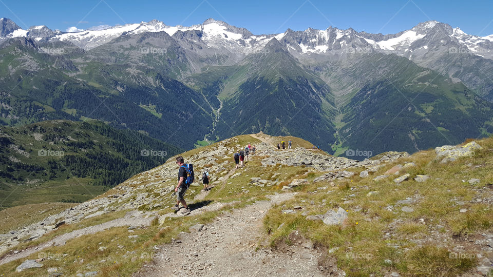 Hikers on a hiking trail at high altitude in the mountains, panoramic view 