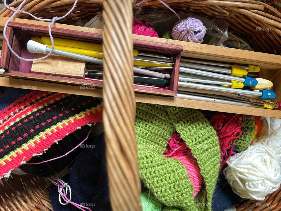 Close up of knitting and crochet hooks on balls of yarn in a basket