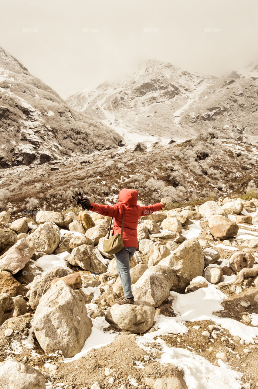 Hiker asia woman in red dress turn back standing and stretching her arms raised in sky after hiking to the top of a himalayan mountain range of everest region. Achievement, Freedom, Success, Happiness concept.