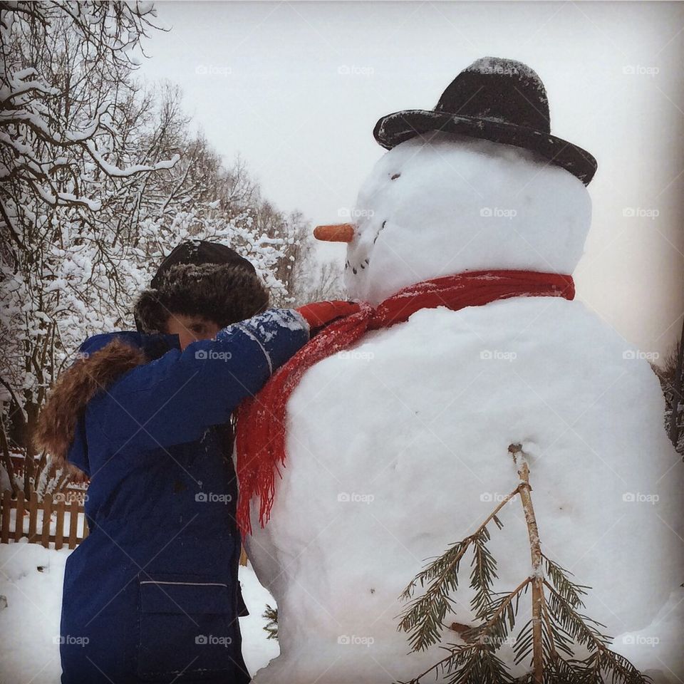 Boy hugging snowman