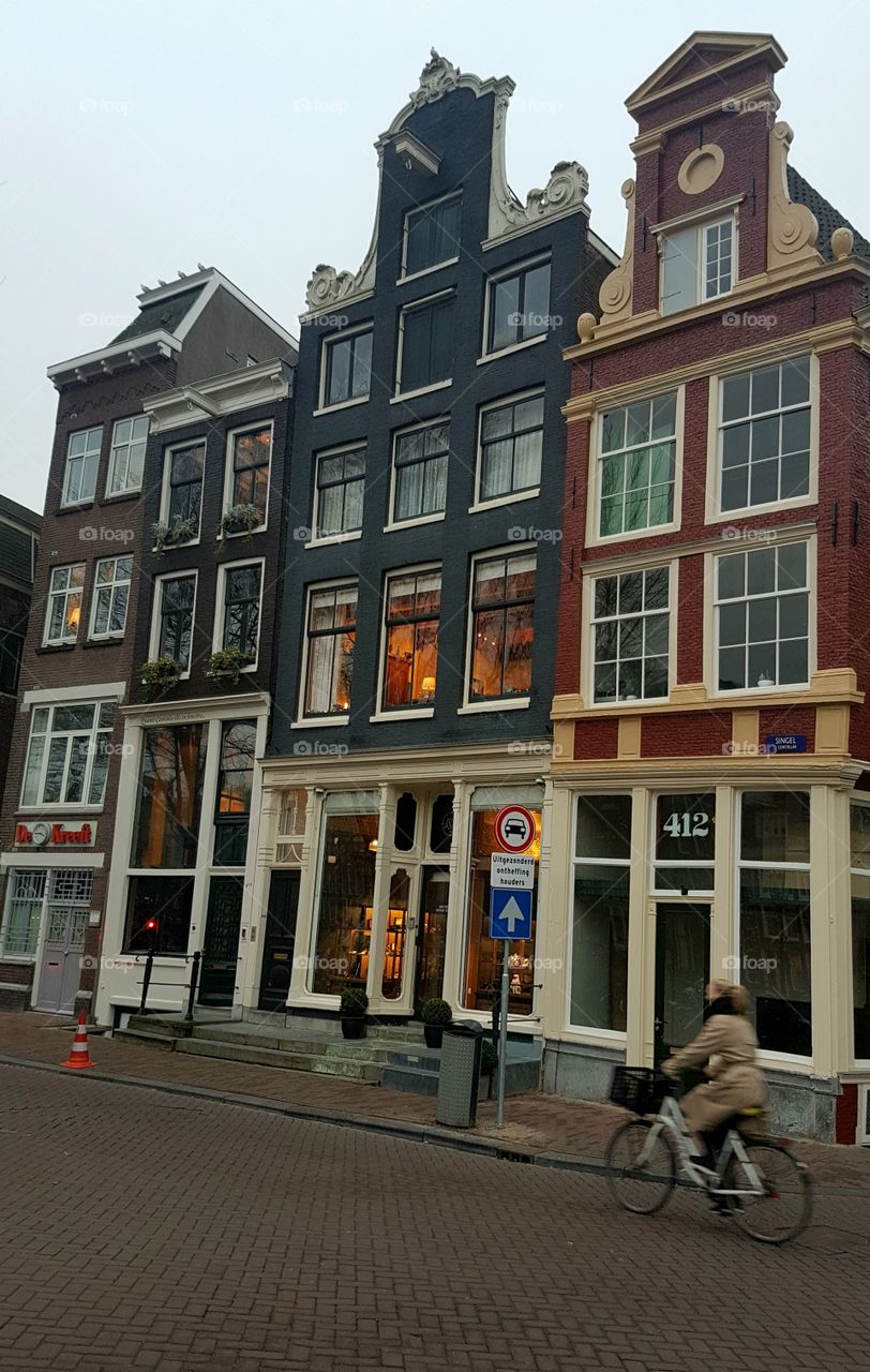 Vintage architecture windows, doors, and roofs on buildings on an old alley street with bicyclist in Amsterdam, Holland, Europe.