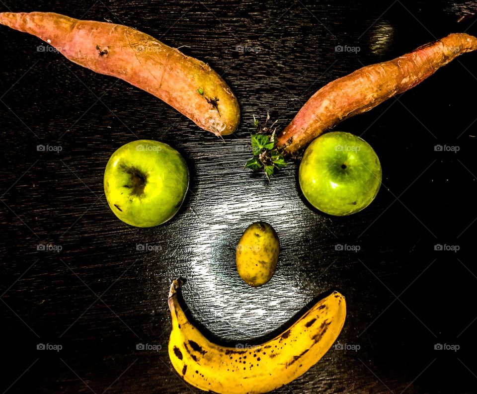 Evil smirking fruit and vegetable face- sweet potato, apples, bananas and a small potato for a nose. 