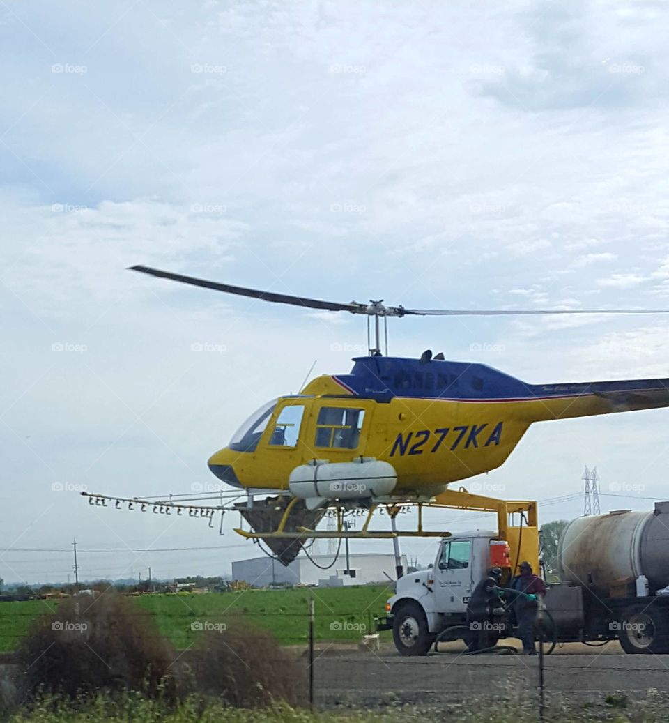 driving along HWY a helicopter loading up on pesticides about to crop dust a field.