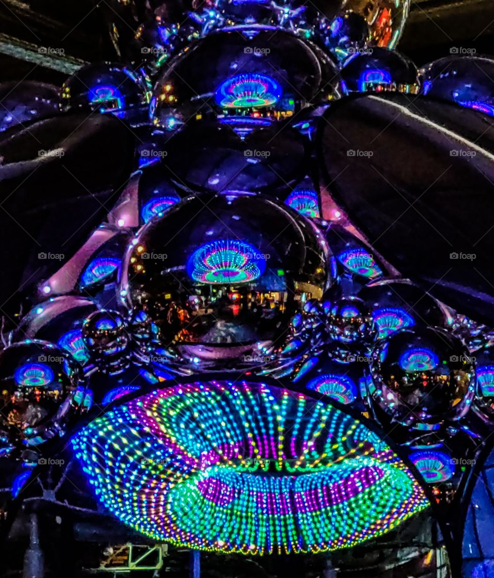 Mirrored sculpture reflecting beautiful array of colorful lights hanging from the ceiling 