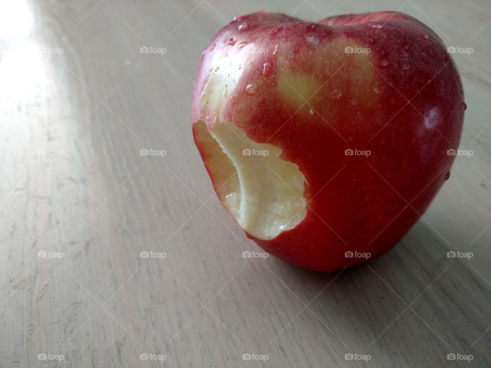 Bitten apple on wood surface.