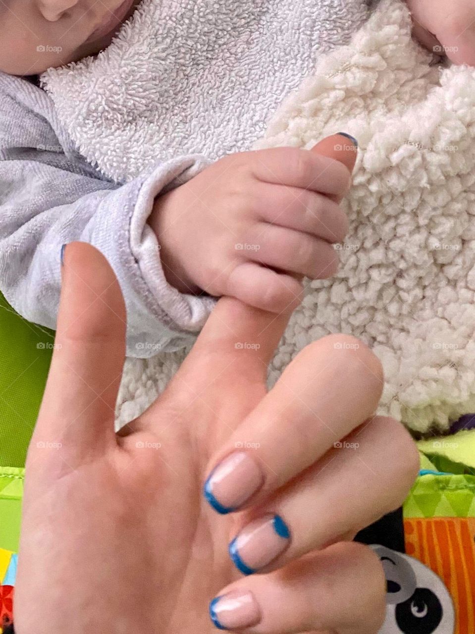 Baby little hand holds finger of his aunt