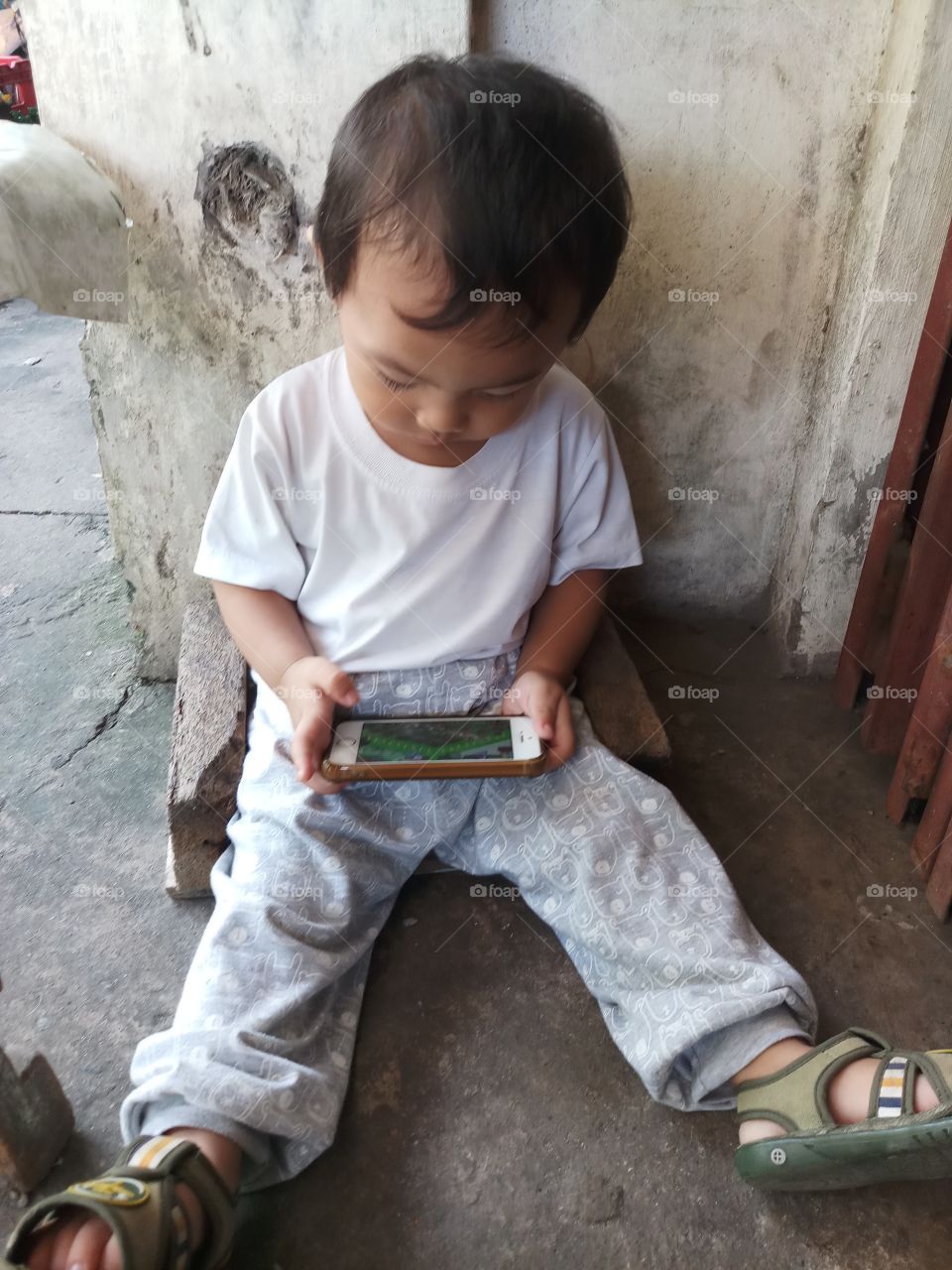 a toddler busy playing using a cellular phone.