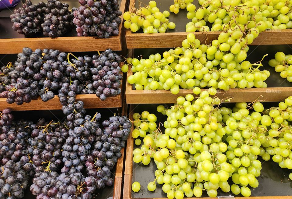 inviting variety of bright green and purple grapes available for sale on wooden levels in an Oregon market