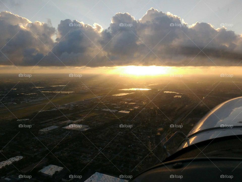 sun low on the horizon seen from an airplane with the engine cowling in view
