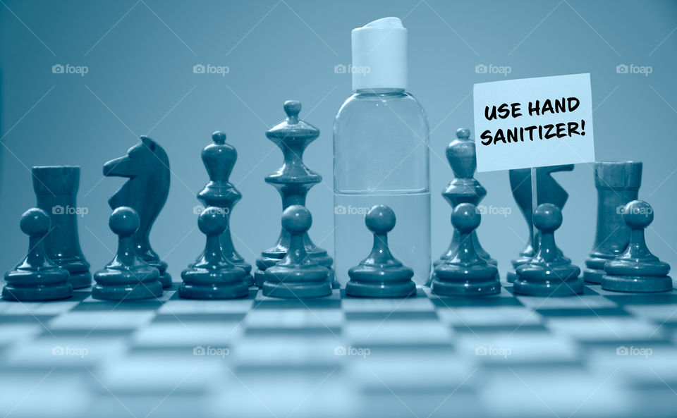 Coronavirus concept image chess pieces and hand sanitizer on chessboard illustrating global struggle against novel covid-19 outbreak with use hand sanitizer sign.