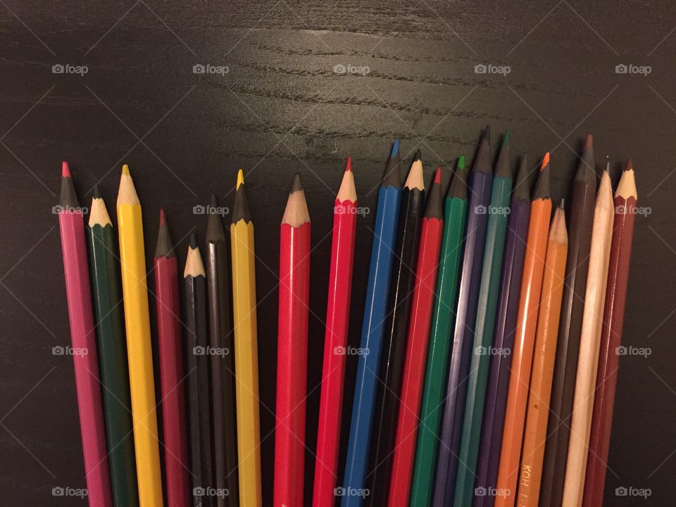 Colored pencils and straight on black desk