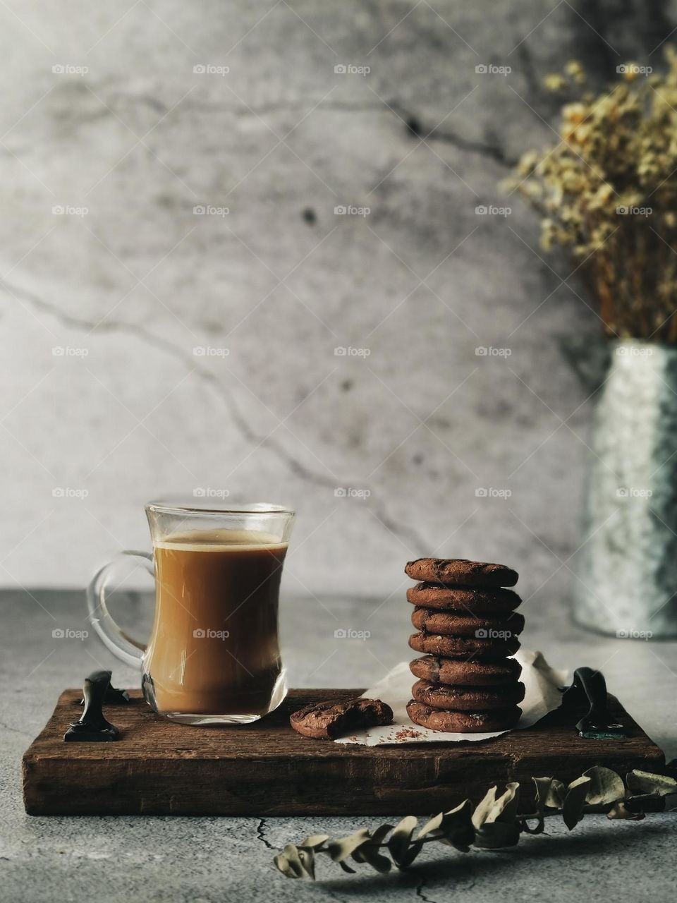 A stack of biscuits and a cup of caffe latte on a wooden board
