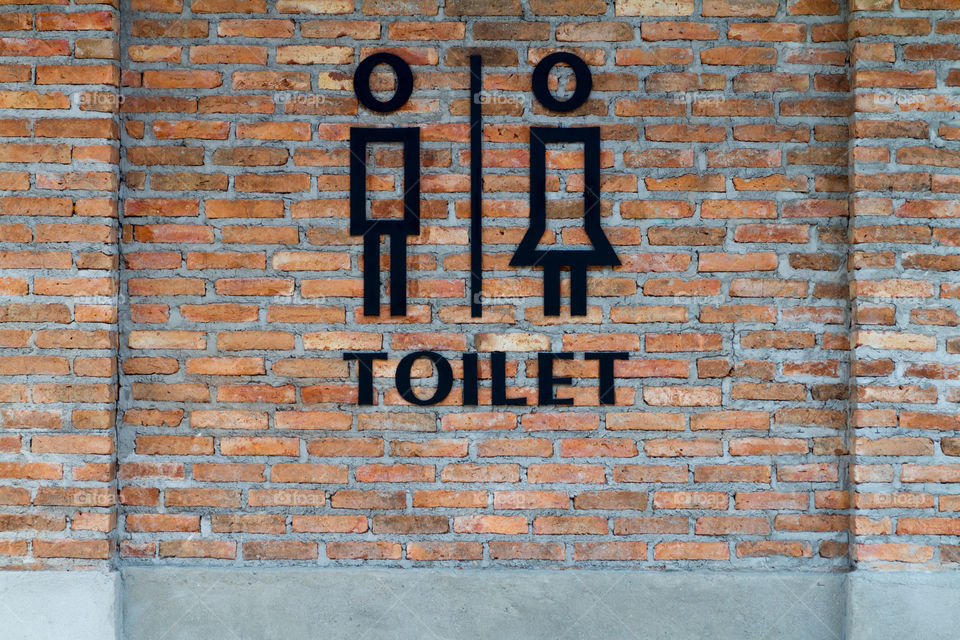 
Black modern public toilet sign on concrete loft style brick wall.