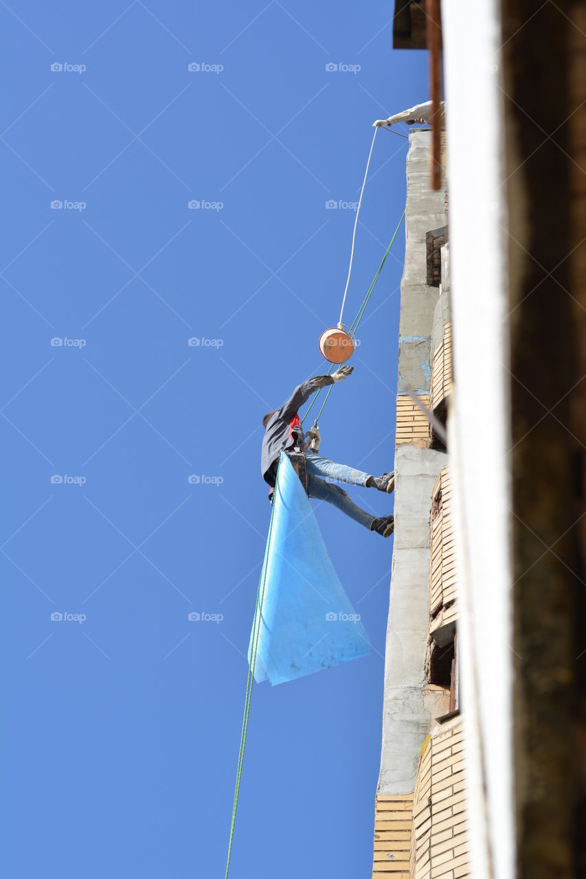 builders working in the house high on a wall blue sky background