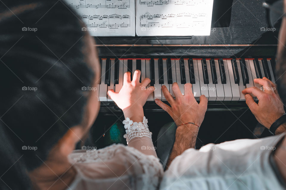 Girl teaches a pupil to play the piano