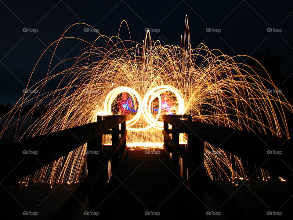 Steel wool sparks flying around the sky exploding like spiders