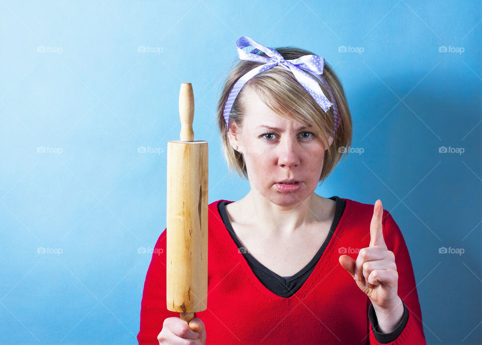 Housewife with rolling pin on blue background.
