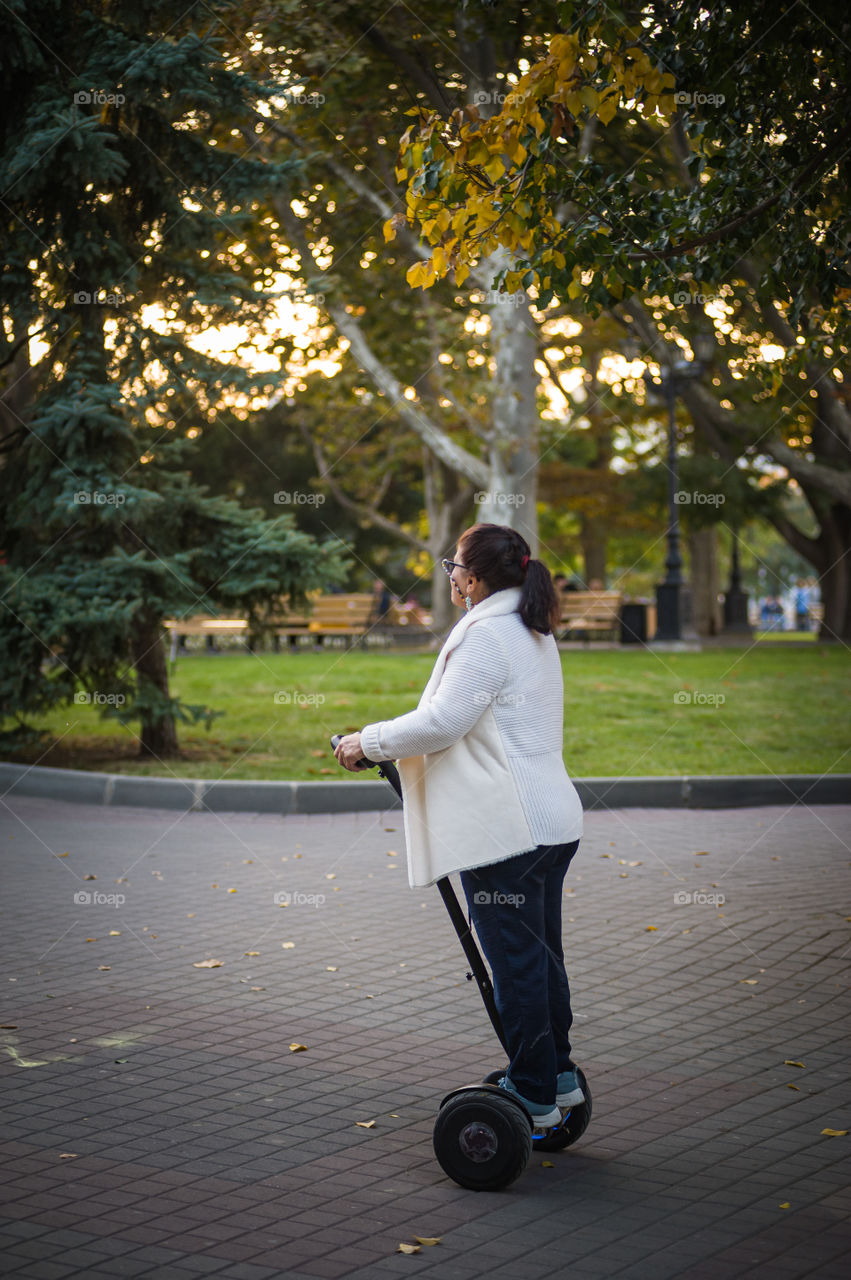 aged woman rides a segway in the autumn park of the city of Sevastopol