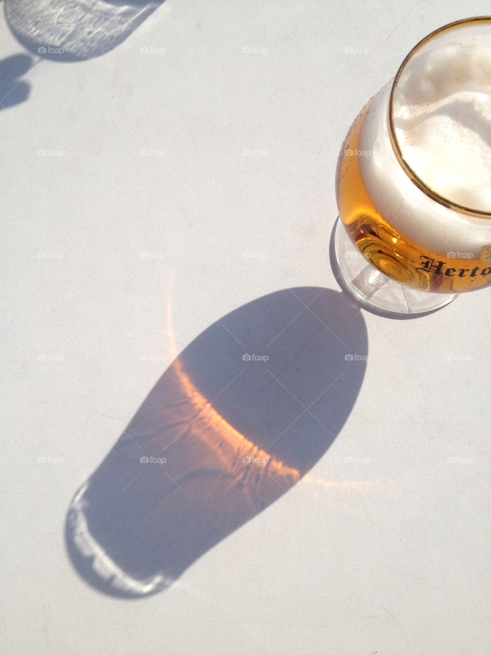 Sunny Beer. Sun casting shadow on beer glass on terrace table. 